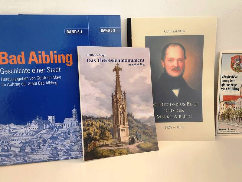 Das Bild zeigt eine Sammlung von vier Büchern über die Geschichte und Persönlichkeiten der Stadt Bad Aibling, aufgestellt auf einem Regal.