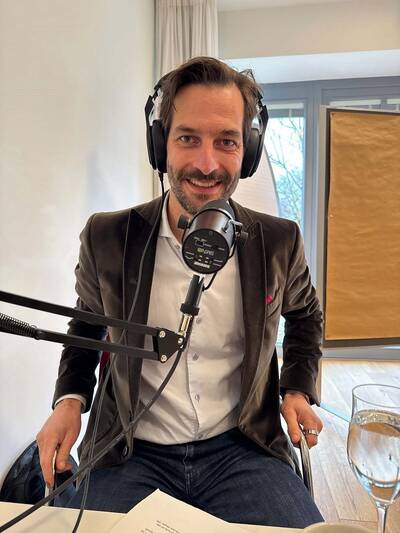 Podcast-Moderator Johann Struck sitzt mit Kopfhörern und einem Mikrofon vor sich an einem Tisch