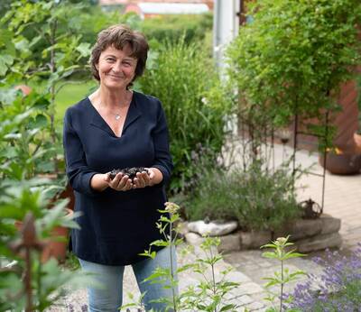 Angelika Panradl steht in einem Garten und hält Aiblinger Moor in ihren Händen.