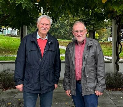 Ulli Nowak und Fritz Schadeck vom AMC Aibling stehen in einem Park, umgeben von Bäumen und grüner Landschaft.