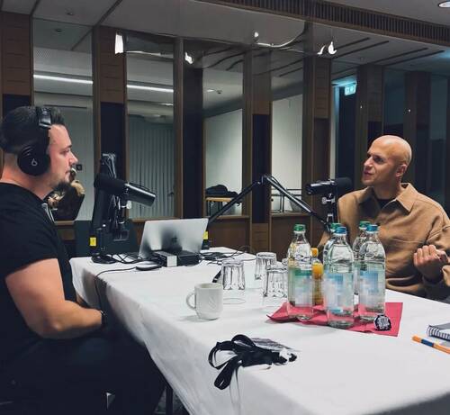Singer-Songwriter MILOW und ein Moderator sitzen sich in einem modernen Studio an einem Tisch mit Mikrofonen und Aufnahmegeräten gegenüber und führen ein Interview