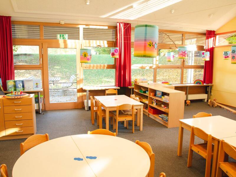 Innenraum des Kindergartens Mariä Himmelfahrt in Bad Aibling mit Tischen und Stühlen.