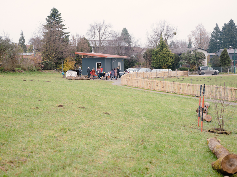 Das Gelände und die Schutzhütte des Waldkindergartens Wurzelburg in Bad Aibling. Zu sehen sind auch Kinder und Eltern.
